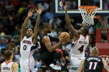 Paul Millsap (4) y Jeff Teague (0) defienden a Dwyane Wade (3).