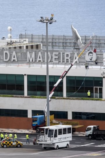 Workers add a sign bearing Cristiano Ronaldo's face to the airport exterior ahead of its 29 March name change to Madeira Cristiano Ronaldo Airport.