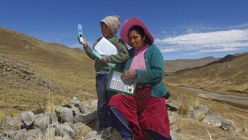 Raymunda Charca (R) helps her ten-year-old son Alvaro Cabrera as he searches for signal on top of a hill in order to attend a virtual class during the COVID-19 novel coronavirus pandemic, near their house in the remote highland community of Conaviri, district of Manazo, in the Peruvian Andes close to Lake Titicaca and the border with Bolivia, early July 24, 2020. - As schools remain closed due to the pandemic, the Cabrera children participate in the "Learn at Home" educational platform which was implemented by the Peruvian Ministry of Education. (Photo by Carlos MAMANI / AFP)