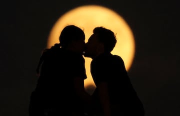 Personas silueteadas contra la luna llena el día del eclipse lunar en las Dunas de Samalayuca, en las afueras de Ciudad Juárez, México.