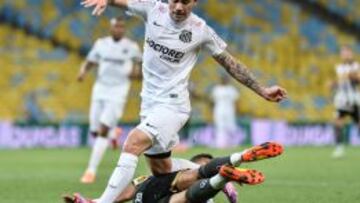 El ex azul luchando una pelota con la camiseta del Santos. 