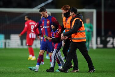 Robert Lewandowski del FC Barcelona acompaña a un espontáneo fuera del terreno de juego.