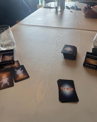 Partido al conocido juego de cartas 'The Mind', un juego de cartas cooperativo diseñado por Wolfgang Warsch, donde 2 a 4 jugadores (mayores de 8 años) deben colaborar para ordenar cartas numeradas del 1 al 100 en orden ascendente sin hablar, hacer señas o comunicarse de ninguna manera, utilizando la concentración y la sincronización mental.