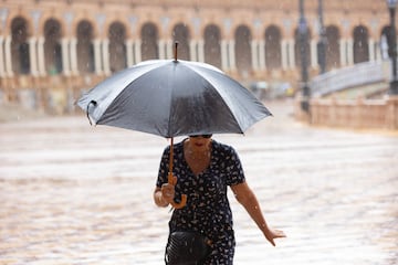 Viandantes protegiéndose de la lluvia en la Plaza de España de Sevilla.