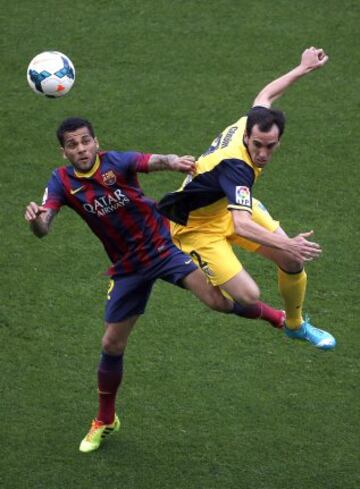 El defensa brasileño del FC Barcelona, Dani Alves (i), salta con el defensa uruguayo del Atlético de Madrid, Diego Godín (d).