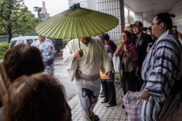 Algunos espectadores observan la llegada de uno de los luchadores de Sumo bajo un enorme "wagasa" el típico paraguas japonés.