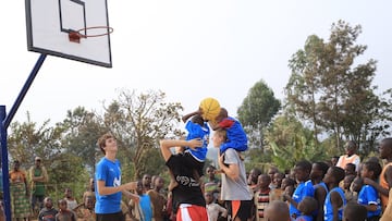 Begoña de Santiago eleva a hombros a un niño para que lance a canasta.