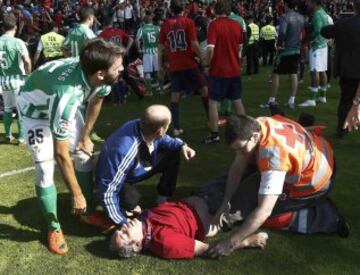 GRA259. PAMPLONA, 18/05/2014.- Un efectivo de Cruz Roja junto al defensa del Betis Jordi Figueras (i) socorren a uno de los heridos en la avalancha registrada en el estadio El Sadar tras el gol de Osasuna, en el minuto 12 del partido contra el Betis, que ha provocado el parón de momento del partido. Ninguna de las personas que han resultado heridas en la avalancha se encuentra en estado grave. EFE/Jesús Diges