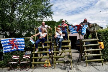 Varios aficionados esperan el paso de los ciclistas con banderas de Luxemburgo.