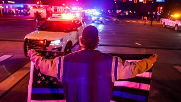 A man holds a thin blue line flag as emergency vehicles escort the body of slain police officer Eric Talley from the scene of a shooting at a King Soopers grocery store in Boulder, Colorado, U.S. March 22. 2021. Picture taken March 22, 2021. Michael Ciagl