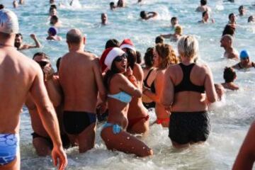 Decenas de ciudadanos participaron este mediodía en el tradicional primer baño del año en la playa de Sant Sebastià del barcelonés barrio de la Barceloneta.