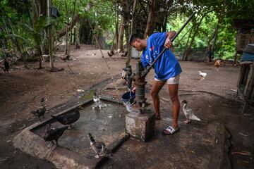 Uno de los usuarios del Centro Deportivo, Vicente, sacando agua de una bomba mientras cuida de sus gallinas tras terminar su entrenamiento de boxeo.