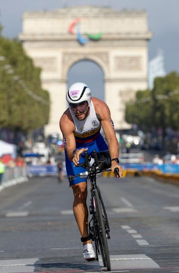 El atleta colombiano Juan Esteban Patino Giraldo se aleja en bicicleta del Arco de Triunfo por los Campos Elíseos durante el Para Triatlón PTS2 Masculino en el Puente Alexandre III. 