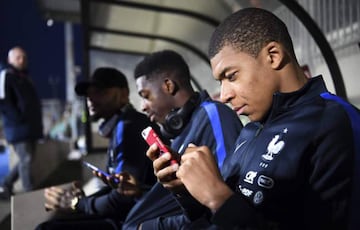 Durante un partido con la Selección de Francia, Mbappé aprovechó su estadía en el banquillo para revisar su celular.