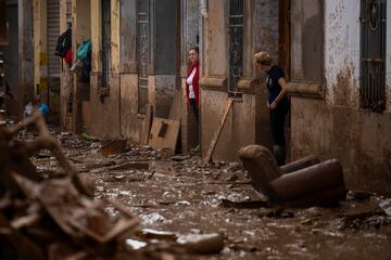 Unas mujeres se encuentran a la entrada de sus casas afectadas por las inundaciones en Masanasa, Valencia.