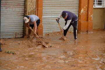 Vecinos de las zonas afectadas intentan limpiar las calles inundadas tras el paso de la DANA.