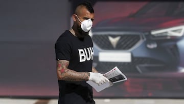 In this photo provided by FC Barcelona, Arturo Vidal walks wearing a protective face mask and gloves at the club's training ground in Barcelona, Spain, on Wednesday May 6, 2020. Soccer players in Spain returned to their team's training camps Wednesday for the first time since the country entered a lockdown nearly two months ago because of the coronavirus pandemic. Players for Barcelona, Real Madrid, Atlético Madrid and other clubs started preparing for the return to training this week, and they were all expected to be tested for COVID-19 and should be cleared to practice once the results are back. (Miguel Ruiz/FC Barcelona via AP)