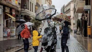 GRAFCVA9224. VALENCIA, 04/11/2020.- Una mujer con tres menores se protegen de la lluvia con paraguas y chubasqueros en una céntrica calle de València el día que la Agencia Estatal de Meteorología (Aemet) mantiene la alerta naranja por lluvias en la Comunitat Valenciana, que se prevén más intensas entre esta tarde y la jornada de mañana por la entrada de viento del este, que afectará sobre todo al litoral sur de Castellón y al interior y prelitoral de la provincia de Valencia. EFE/Biel Aliño
