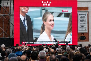 Varias personas siguen en pantallas, preparadas para la ocasión, el Juramento de la Constitución de la Princesa Leonor, en la Puerta del Sol.