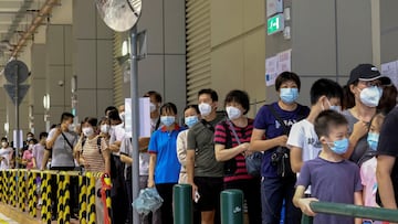 FILE PHOTO: Residents wearing face masks line up to get tested for the coronavirus disease (COVID-19) in Macau, China July 4, 2022. REUTERS/John Mak/File Photo