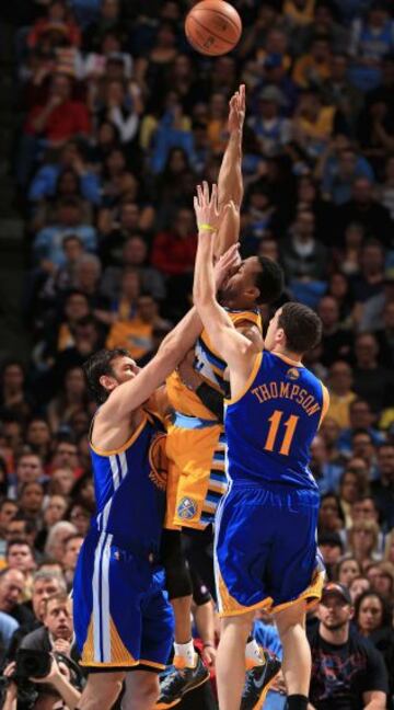 Andre Iguodala de los Denver Nuggets en un salto entre Andrew Bogut (12) y Klay Thompson (11) de Golden State Warriors.