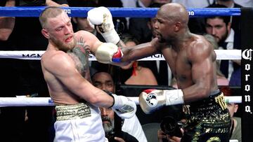 Boxer Floyd Mayweather Jr. (R) punches mixed martial arts star Conor McGregor during their fight at the T-Mobile Arena in Las Vegas, Nevada on August 26, 2017. 
 Floyd Mayweather outclassed Conor McGregor with a 10th-round stoppage on August 26 to win their money-spinning superfight and clinch his 50th straight victory. / AFP PHOTO / John Gurzinski