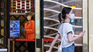 A woman wearing a face mask walks past a staff member inside the Grand Lisboa casino amid the coronavirus disease (COVID-19) outbreak in Macau, China July 4, 2022. REUTERS/John Mak NO RESALES. NO ARCHIVES.
