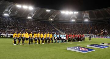 Los equipos posan en el centro del campo. 