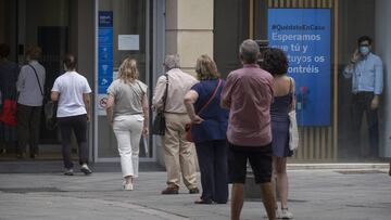 Imagen de varias personas acudiendo a una entidad bancaria guardando la distancia de seguridad.