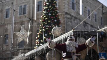 JERUSALEM - DECEMBER 22: A man dressed up as Santa Claus and a woman dressed up as an elf tour the city walls with a camel ahead of Christmas in Jerusalem on December 22, 2022. (Photo by Mostafa Alkharouf/Anadolu Agency via Getty Images)