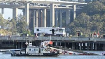 Un bote de la Polic&iacute;a de San Francisco patrulla junto a los restos del catamar&aacute;n AC72 del equipo Artemis.