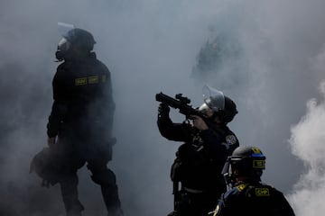 Un agente de policía apunta con un arma en medio del humo durante una protesta contra las redadas federales de inmigración en el centro de Los Ángeles.