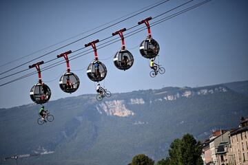 Francia y sus localidades siempre se engalanan para celebrar el paso del Tour y sus habitantes se esfuerzan en dejar imágenes tan curiosas y llamativas como esta. Tres ciclistas vuelan enganchados al teleférico que sube a la Bastilla de Grenoble, una fortaleza del siglo XIX que domina la ciudad desde donde partió la etapa del día 16.