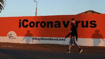 FILE PHOTO: A man walks past the words "Coronavirus" painted on a wall, amid the spread of the coronavirus disease (COVID-19) outbreak, in Soweto, South Africa, May 31, 2020. REUTERS/Siphiwe Sibeko/File Photo