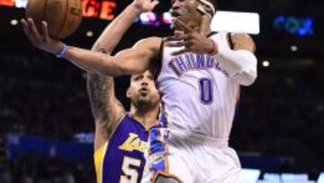 Robert Sacre trata de parar a Russell Westbrook.
