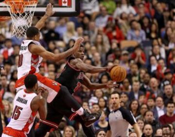 Jimmy Butler pasa el balón ante el acoso de dos 'raptors'.