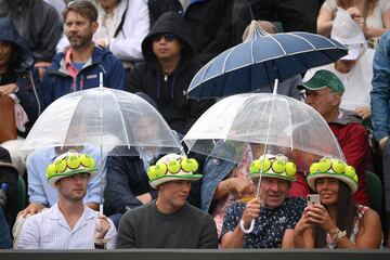 En el segundo día de competición, la lluvia hizo acto de presencia sobre la instalación londinense, pero los aficionados no desistieron de presenciar en directo su deporte favorito. En la imagen se puede ver a un grupo bajo sus paraguas haciendo frente a las inclemencias del tiempo en el All England Tennis Club.
