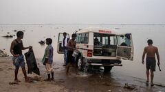 Varios j&oacute;venes lavan una ambulancia cerca de un hospital de la India.