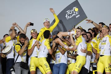 Los ciclistas del equipo UAE Team Emirates mantean a Tadej Pogacar en el podio. 