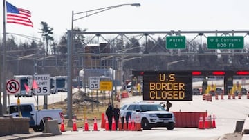 Los oficiales de aduanas de EE.UU. se paran junto a un cartel que dice que la frontera de EE.UU. está cerrada en la frontera entre EE.UU. y Canadá en Lansdowne, Ontario, el 22 de marzo de 2020.