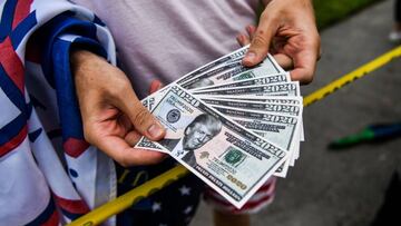 A man holds fake currency bearing the image of US President Donald Trump as he participates in a &quot;Freedom Rally&quot; protest in support of opening Florida in South Beach in Miami, on May 10, 2020. (Photo by CHANDAN KHANNA / AFP)