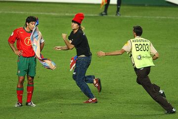 A steward chases a spectator, center, who threw a flag into the face of Luis Figo of Portugal during the Euro 2004 (AP Photo/Luca Bruno) 