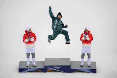 El medallista de oro brasileño Lucas Pinheiro Braathen (C) salta al podio flanqueado por el medallista de plata suizo Marco Odermatt (I) y el medallista de bronce suizo Loic Meillard durante el podio del evento de esquí alpino de slalom gigante