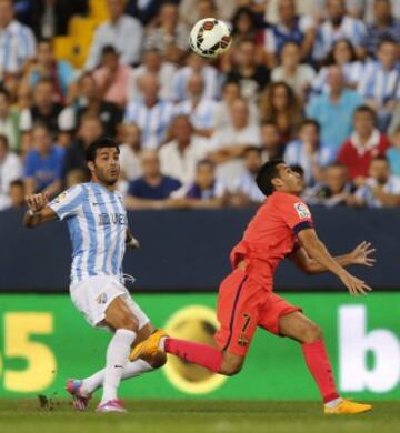 El defensa del Málaga CF, Miguel Torres, lucha el balón con el delantero del FC Barcelona, Pedro Rodríguez, durante el encuentro de la quinta jornada de Liga en Primera División que se disputa esta noche en el estadio de La Rosaleda, en Málaga.