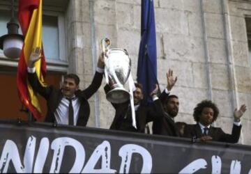 Los jugadores del Real Madrid, Iker Casillas (i), Sergio Ramos, Álvaro Arbeloa (2d) y el brasileño Marcelo Vieira, saludan a los aficionados desde el balcón la sede de la Comunidad de Madrid con la copa de la Liga de Campeones, tras vencer al Atlético de Madrid en la final disputada ayer en Lisboa.