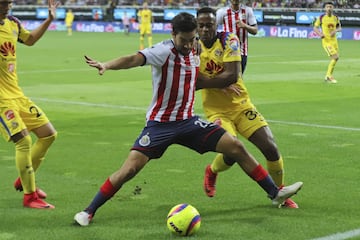 Rodolfo Pizarro protege el balón ante el acecho de dos jugadores del América.