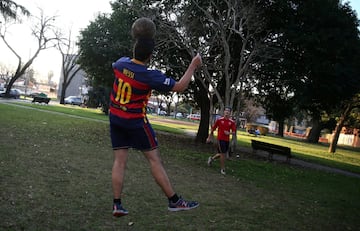 A boy wearing a Barcelona jersey with Lionel Messi's name playing football in a park outside Messi's childhood school in Rosario.