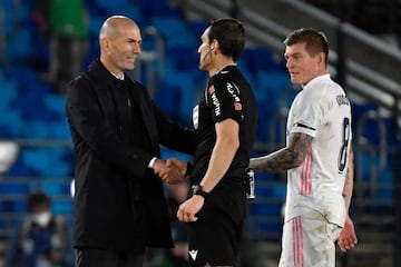 Real Madrid's French coach Zinedine Zidane (L) shakes hands with Spanish referee Juan Martinez Munuera (C) as Real Madrid's German midfielder Toni Kroos walks past during the Spanish League football match between Real Madrid CF and Sevilla FC at the Alfre