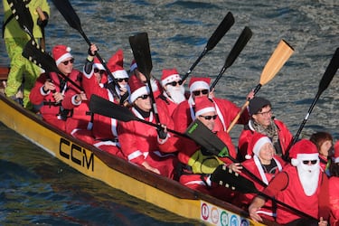 Personas vestidas de Papá Noel reman durantela  regata navideña en el Gran Canal de Venecia.