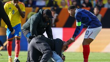 France's forward #10 Kylian Mbappe assists a fan who jumped onto the field to greet him as he's restrained by security at the end of a friendly football match between Colombia and France at Northwest Stadium in Landover, Maryland, on March 29, 2026. (Photo by FRANCK FIFE / AFP)